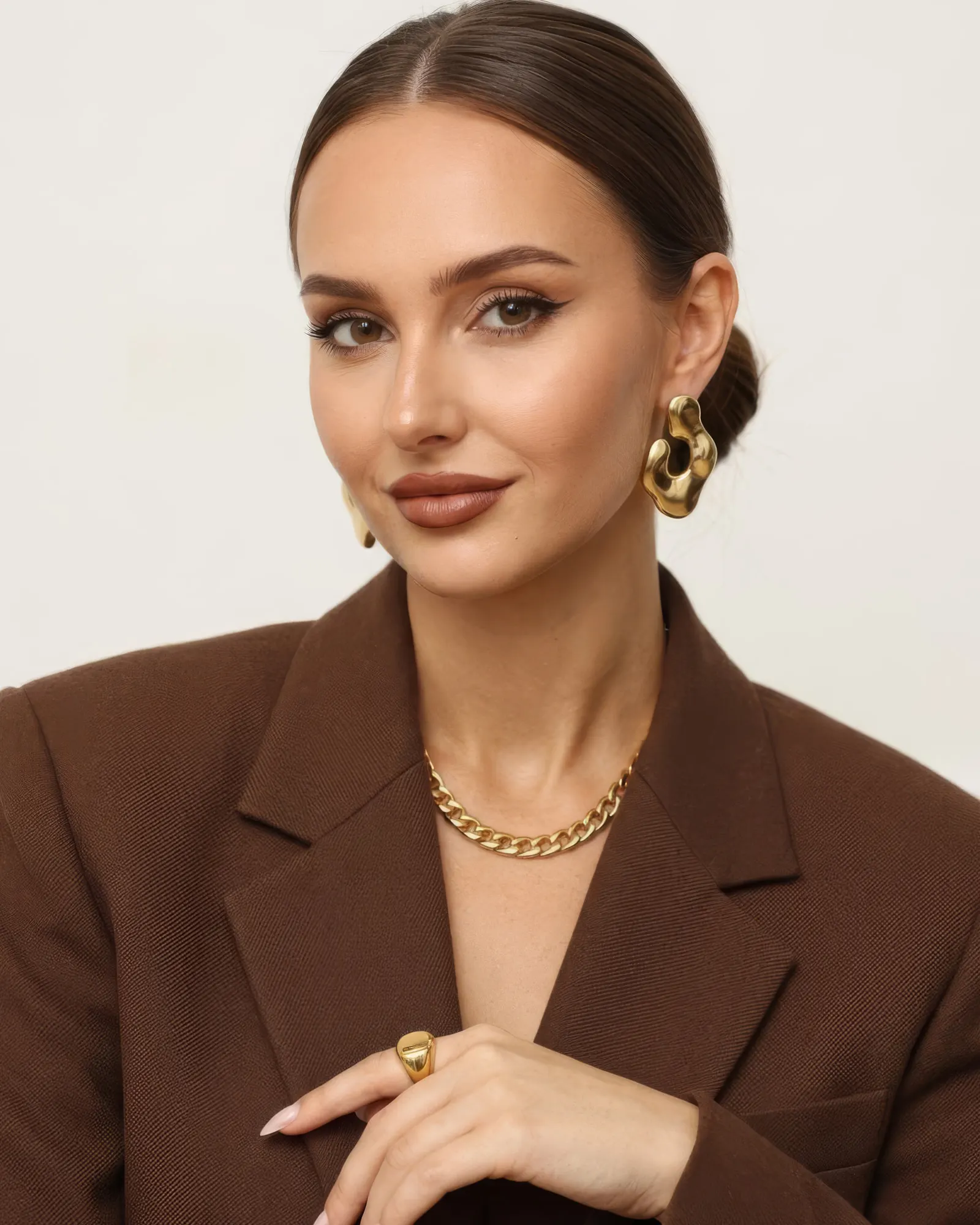 Nele Mara im braunen Blazer, die Hand am Revers zeigt schmale Nude-Nägel - Lumara Aesthetica, Nagelstudio Rostock